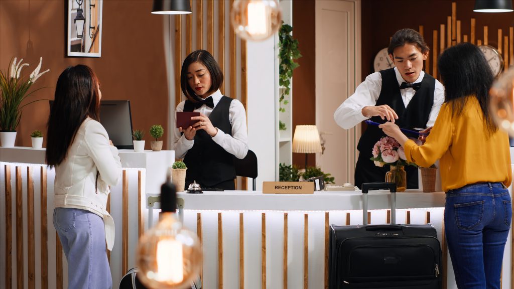 tourists going through check in process at hotel reception desk
